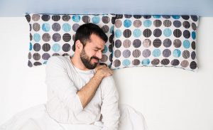A man holding his shoulder in pain after sleeping