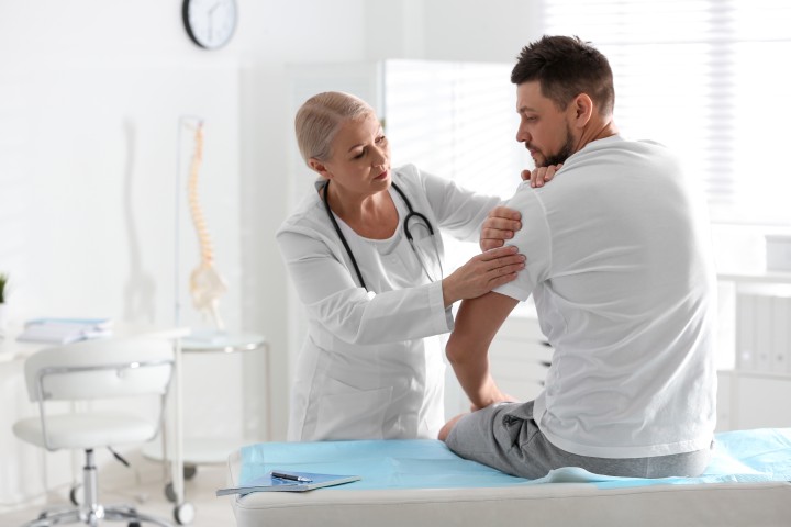 Male orthopedist examining patient’s arm in clinic